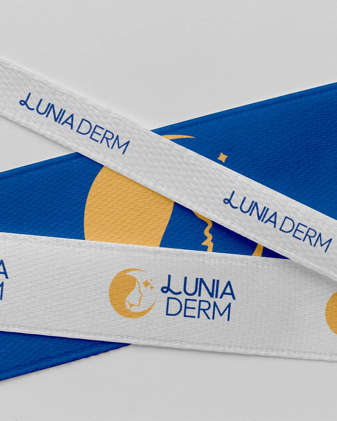 White and navy ribbons printed with the Lunia Derm logo